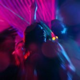 Group of party people - a man and women - dancing in a disco club to the music