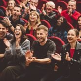 Group of excited people clapping hands in the theater.